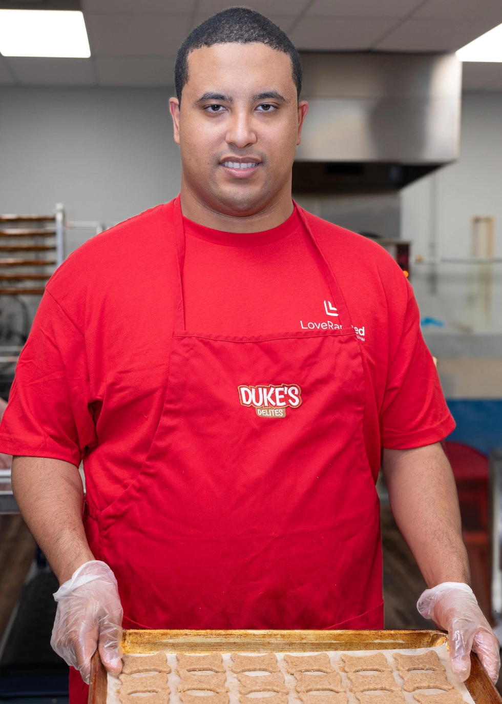 Man holding tray of baked goods.