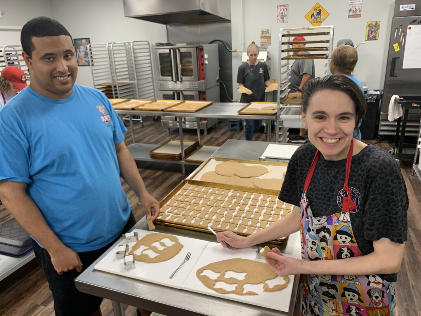 Two people decorating gingerbread cookies in a kitchen.